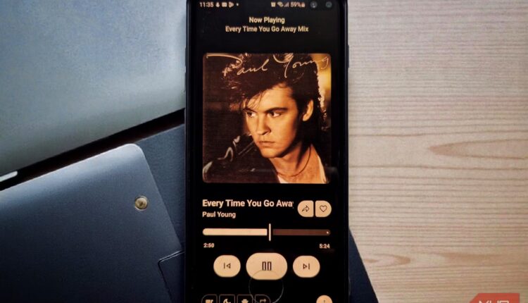 A smartphone on a desk displaying a music app s now playing screen.jpeg