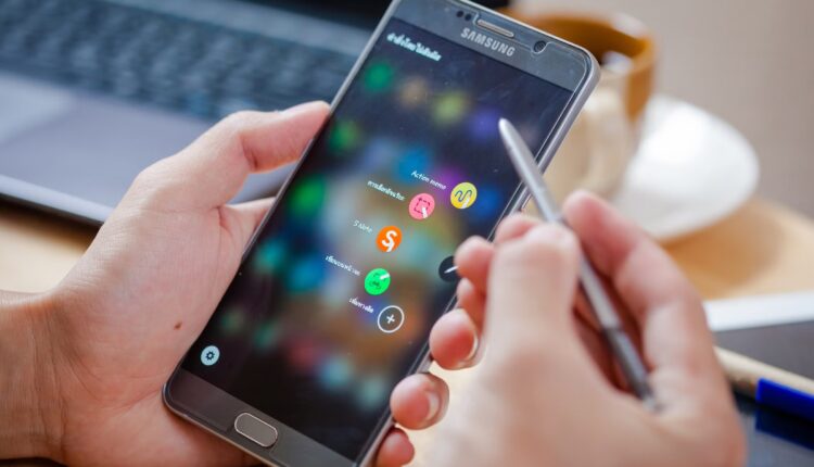 A man holding the galaxy note 5 and trying to use the s pen.jpg