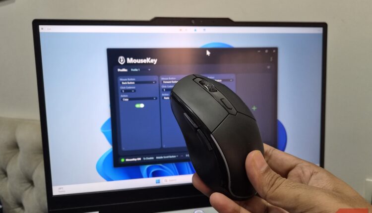 A hand holding a mouse with laptop in background showing mousekey app.jpg