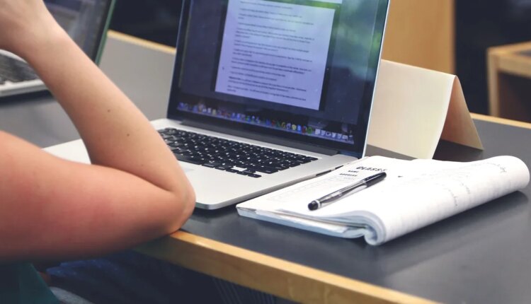 Student taking notes in classroom with laptop macbook.jpg